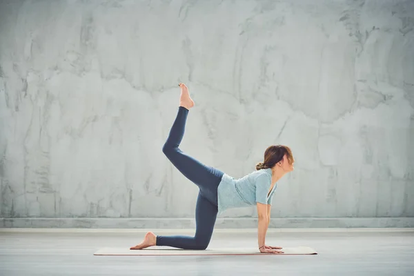 Mavi kıyafetli güzel Kafkas esmer mat bir Bacaklı Kutu yoga poz yapıyor. — Stok fotoğraf