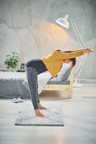 Longitud completa de hermosa morena en forma estirándose en la alfombra por la mañana. Concepto de práctica de yoga . — Foto de Stock