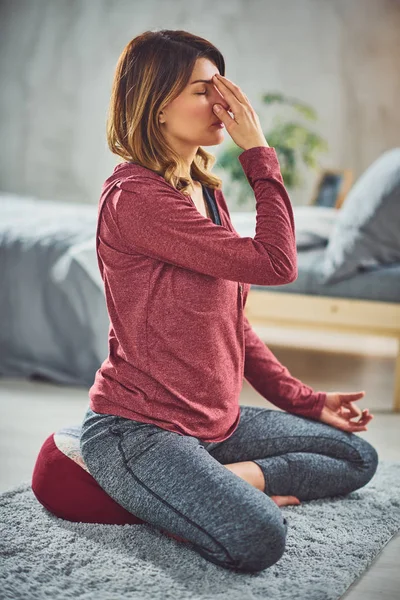 Affascinante bruna caucasica seduta sul letto in camera da letto e facendo esercizi di yoga . — Foto Stock