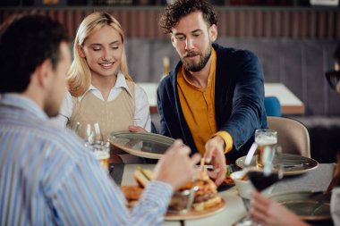 Çok ırklı arkadaşlar restoranda oturan, alkol içme, sohbet ve akşam yemeği için hamburger yeme.