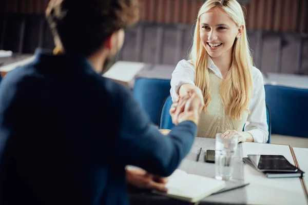 Two business partners shaking hands while sitting in coffee shop. — Stock Photo, Image