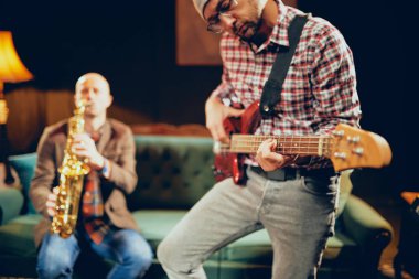 Bas gitar ve saksafon ev stüdyosunda oynayan iki beyaz büyük müzisyenler.