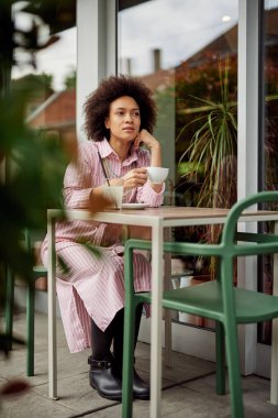 Çekici karışık yarış kadın kafede oturan ve onun kahve zevk.