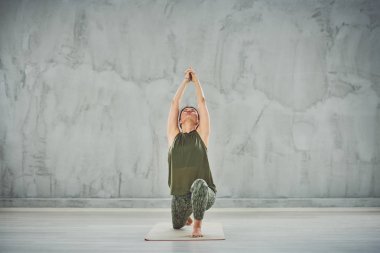 Yeşil kıyafet Warrior I yoga poz odaklanmış büyüleyici Kafkas esmer.