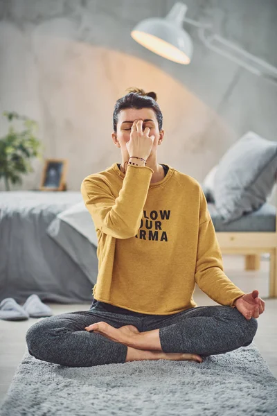 Hermosa morena caucásica sentada en pose de loto yoga y practicando la respiración. Dormitorio interior, rutina de la mañana . — Foto de Stock