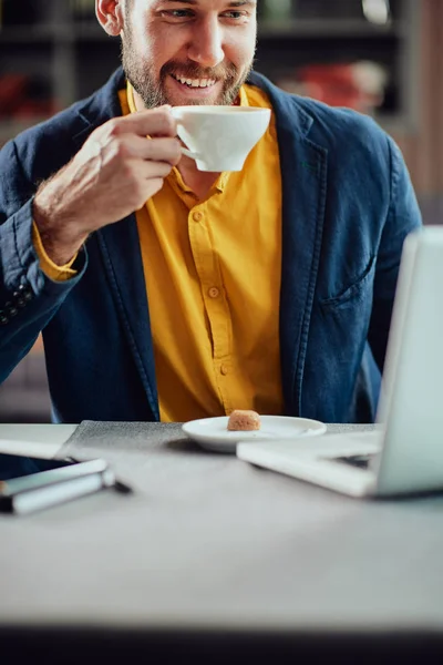 Porträtt av unga moderna kaukasiska man klädd smart casual sittande i cafeteria och dricka färskt kaffe. — Stockfoto