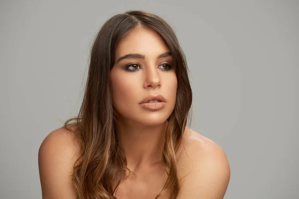 Headshot of beautiful Caucasian brunette posing in front of grey background. Beauty photography. — Stock Photo, Image