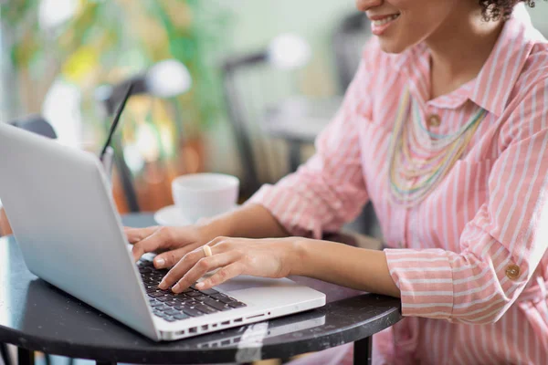 Donna razza mista che utilizza il computer portatile in caffè. le mani sono sulla tastiera . — Foto Stock