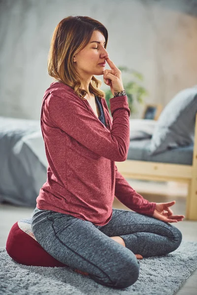 Hermosa morena caucásica sentada en pose de loto yoga y practicando la respiración. Dormitorio interior, rutina de la mañana . — Foto de Stock