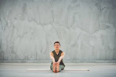 Sevimli Kafkas esmer spor giyim egzersiz mat oturan ve yoga yapıyor.