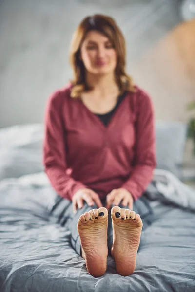 Encantadora morena caucásica sentada en la cama en el dormitorio y haciendo ejercicios de yoga . — Foto de Stock