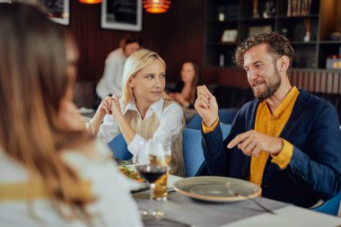 Çok ırklı arkadaşlar restoranda oturan, alkol içme, sohbet ve akşam yemeği için hamburger yeme.