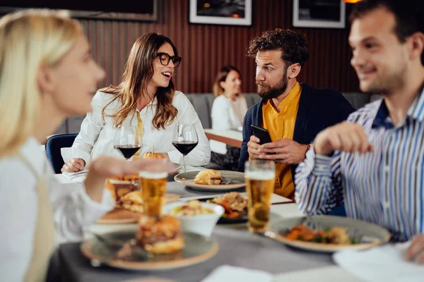 레스토랑에 앉아 술을 마시고, 채팅을하고, 저녁 식사를 위해 햄버거를 먹는 다민족 친구들. — 스톡 사진