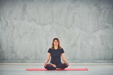 Nilüfer duruşu içinde paspas Üzerinde oturan beutiful kadın.