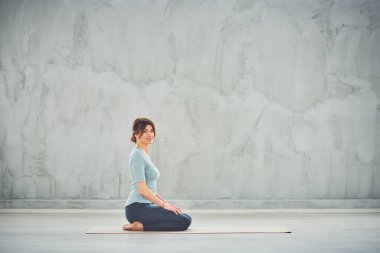 Thunderbolt yoga poz oturan sprtswear güzel Kafkas esmer Yan görünümü.