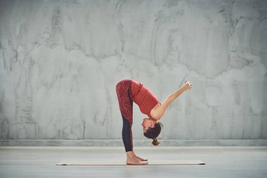 Kırmızı spor güzel Kafkas esmer yan görünümü Standing Forward Bend yoga duruş paspas üzerinde yalınayak ayakta giymek.