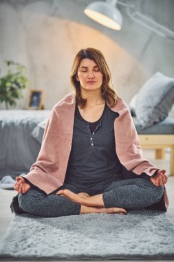 Güzel Kafkas esmer Lotus yoga duruş yatak odasında halı üzerinde oturan.
