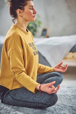 Güzel Kafkas esmer Lotus yoga duruş yatak odasında halı üzerinde oturan.