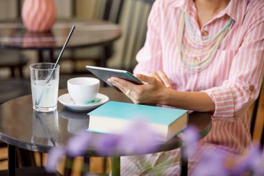 Çekici karışık yarış kadın çizgili pembe elbise kafede oturan ve tablet kullanarak.