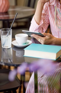 Çekici karışık yarış kadın çizgili pembe elbise kafede oturan ve tablet kullanarak.