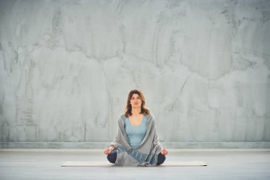 Nilüfer duruşu içinde paspas Üzerinde oturan beutiful kadın.