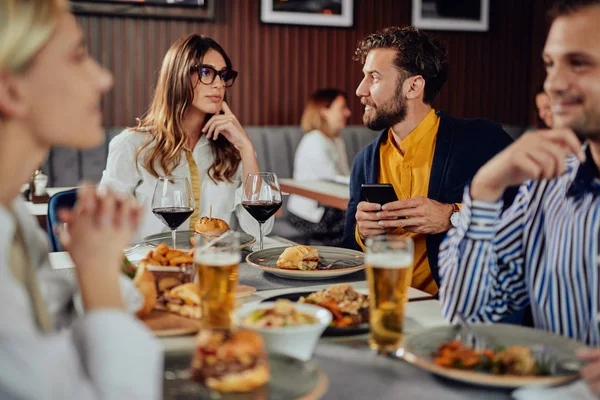Amigos multiétnicos sentados en el restaurante, bebiendo alcohol, charlando y comiendo hamburguesas para cenar . —  Fotos de Stock
