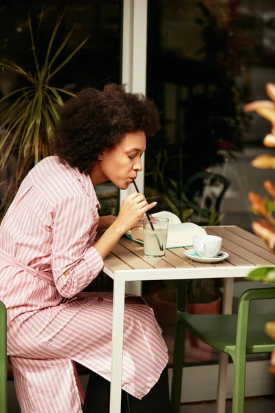 Mooie lachende gemengde race vrouw zittend in café en limonade drinken. — Stockfoto