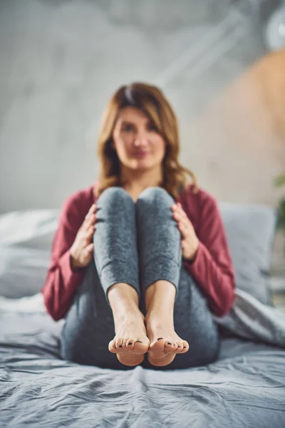 Encantadora morena caucásica sentada en la cama en el dormitorio y haciendo ejercicios de yoga . — Foto de Stock