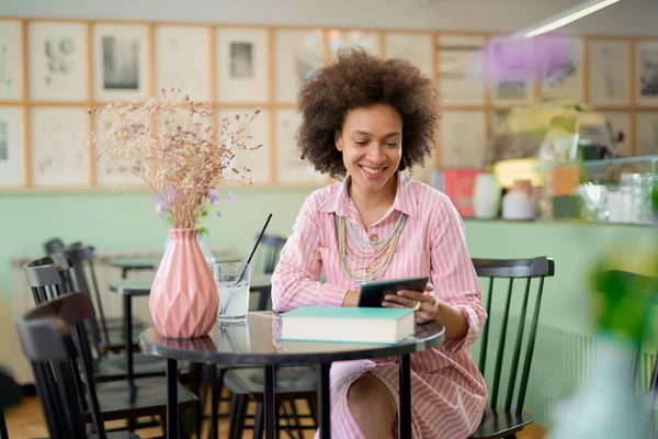 Aantrekkelijke mixed race vrouw in gestreepte roze jurk zitten in Cafe en het gebruik van Tablet. — Stockfoto