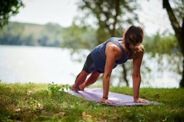 Fit Kafkas esmer sabah doğada mat ters tahta yapıyor. Yoga pratik kavramı.