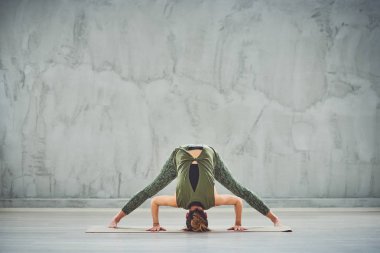 Kırmızı spor giyim güzel ince esmer Geniş Bacaklı İleri Viraj I yoga mat yalınayak poz yapıyor.