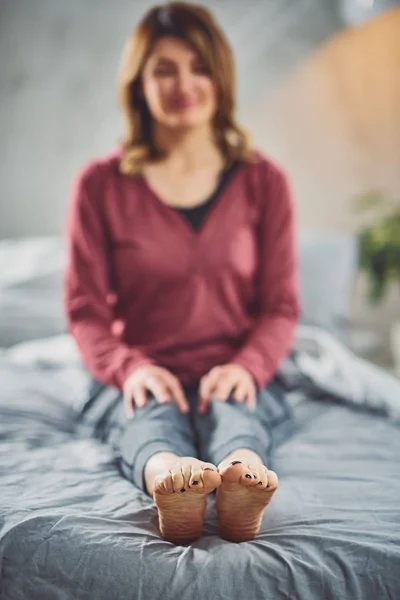 Encantadora morena caucásica sentada en la cama en el dormitorio y haciendo ejercicios de yoga . — Foto de Stock