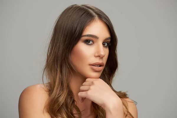 Headshot of beautiful Caucasian brunette posing in front of grey background. Beauty photography. — Stock Photo, Image