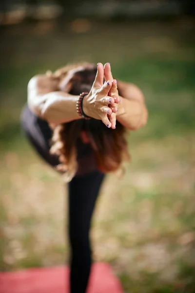 Mujer caucásica enfocada de pie en pose de yoga Guerrero III. Naturaleza exterior. Enfoque selectivo en las manos . —  Fotos de Stock