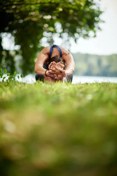 Ajuste sano Caucausain mujer sentada en la estera en la naturaleza en Seated Forward Bend . — Foto de Stock