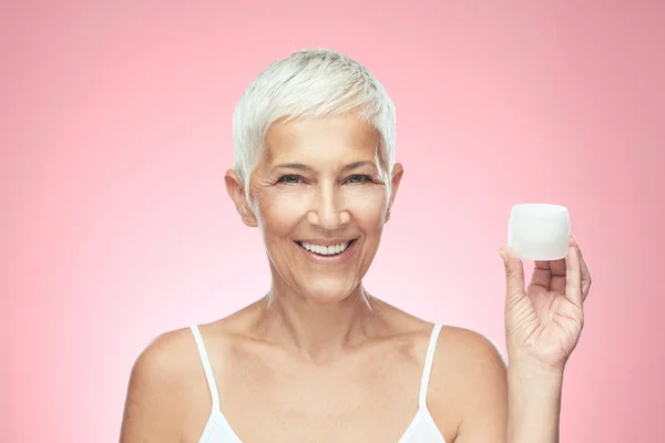 Beautiful smiling senior woman with short gray hair posing in front of gray background. Beauty photography. — Stock Photo, Image