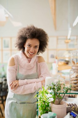 Pembe balıkçı yaka kazak ve çerez ile kavanoz yanında poz önlük ile çekici karışık ırk çalışanı. Pastane içi.