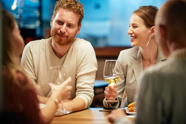 Beste Freunde sitzen zum Abendessen im Restaurant, trinken Wein und plaudern. — Stockfoto