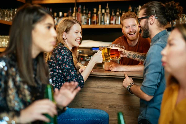 Vrienden staan in de bar en toasten met bier. — Stockfoto