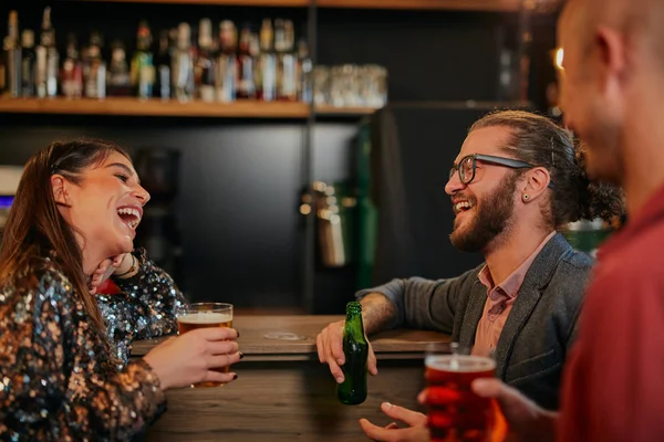Blank stel leunend op een bar, bier drinkend en pratend. Nachtleven. Pub interieur. — Stockfoto