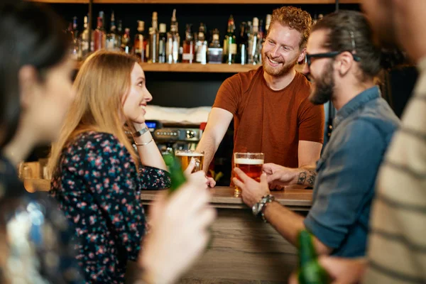 Gruppe von Freunden, die Bier trinken, plaudern und sich mit dem Barmann unterhalten. Nacht aus. Kneipeninterieur. — Stockfoto