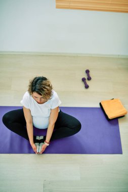Nilüfer pozisyonu almış, meditasyon yapan orta yaşlı hamile bir kadın..