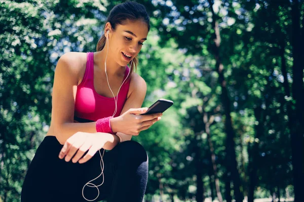 若い魅力的な白人の笑顔女性ランナーは 実行から休憩を取り スマートフォンを使用して — ストック写真