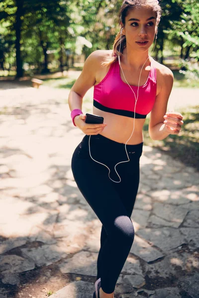 Joven Atractiva Deportista Caucásica Sosteniendo Teléfono Inteligente Mientras Corre Naturaleza — Foto de Stock