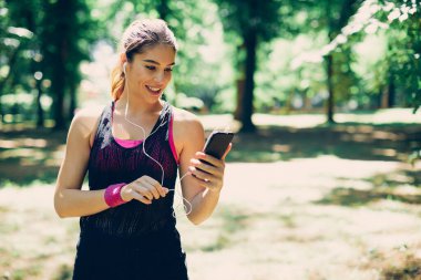 Doğada ayakta duran ve akıllı telefon kullanan güzel beyaz kadın..