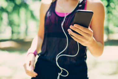 Güzel güneşli bir günde doğada dikilirken akıllı telefon kullanan çekici beyaz kadın..