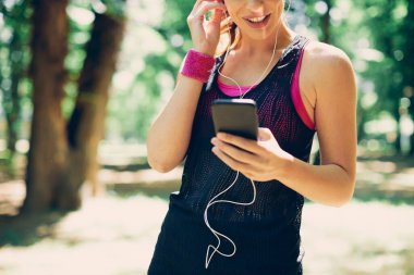 Güzel güneşli bir günde doğada dururken akıllı telefon kullanan çekici beyaz kadın..