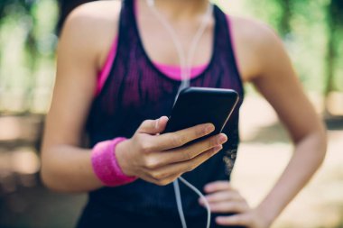 Güzel güneşli bir günde doğada dikilirken akıllı telefon kullanan çekici beyaz kadın..