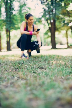 Genç beyaz kadın koşucunun bulanık bir resmi. Koştuktan sonra çömelmiş ve dinleniyor..