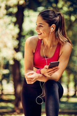 Genç, çekici, beyaz kadın koşucu. Koştuktan sonra ara veriyor ve akıllı telefon kullanıyor..